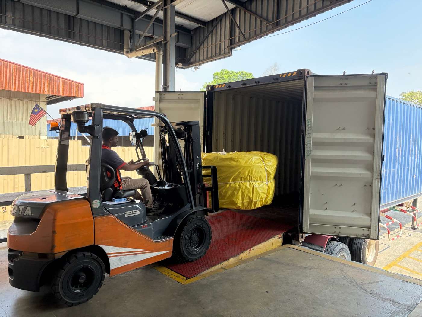 A forklift loading a wrapped bale of rope and netting into a shipping container at Jaya Nets for export