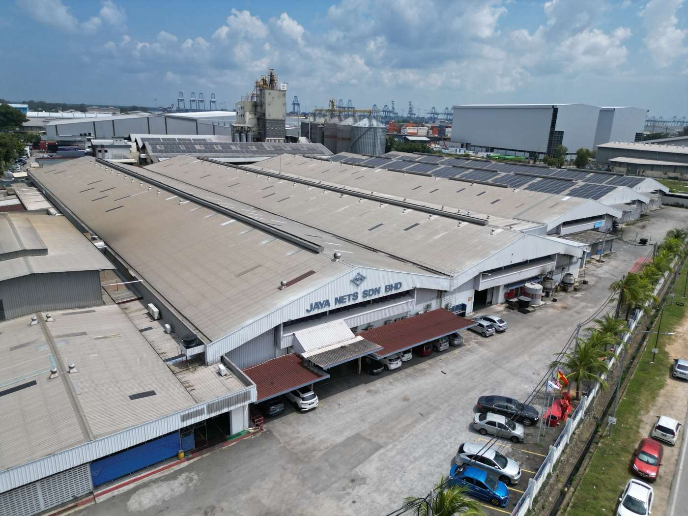 Aerial view of the Jaya Nets factory in Klang, with rooftop solar panels and Port Klang in the distance